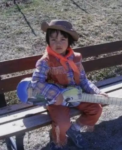 Eidos as a kid with a cardboard guitar that he built